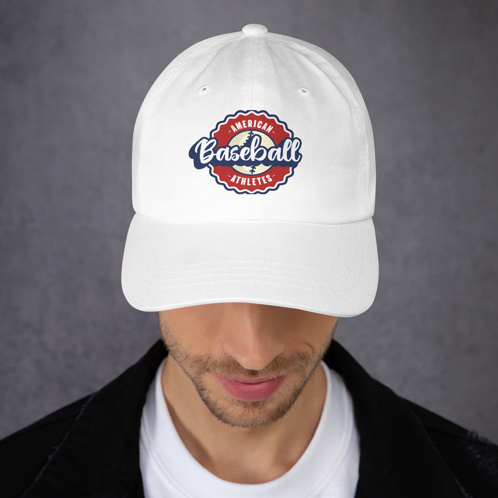 A man wearing a white baseball cap with a red, white, and blue 'American Baseball Athlete' logo patch on the front, photographed against a textured gray background.