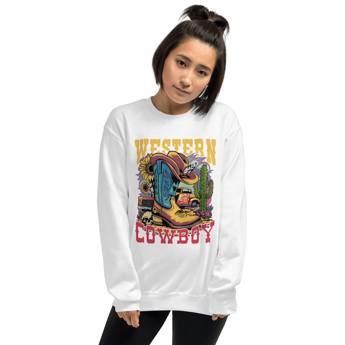 A woman wearing a white crewneck sweatshirt with a colorful 'Western Cowboy' graphic print featuring a cowboy boot, cactus, and car, set against a plain white background.