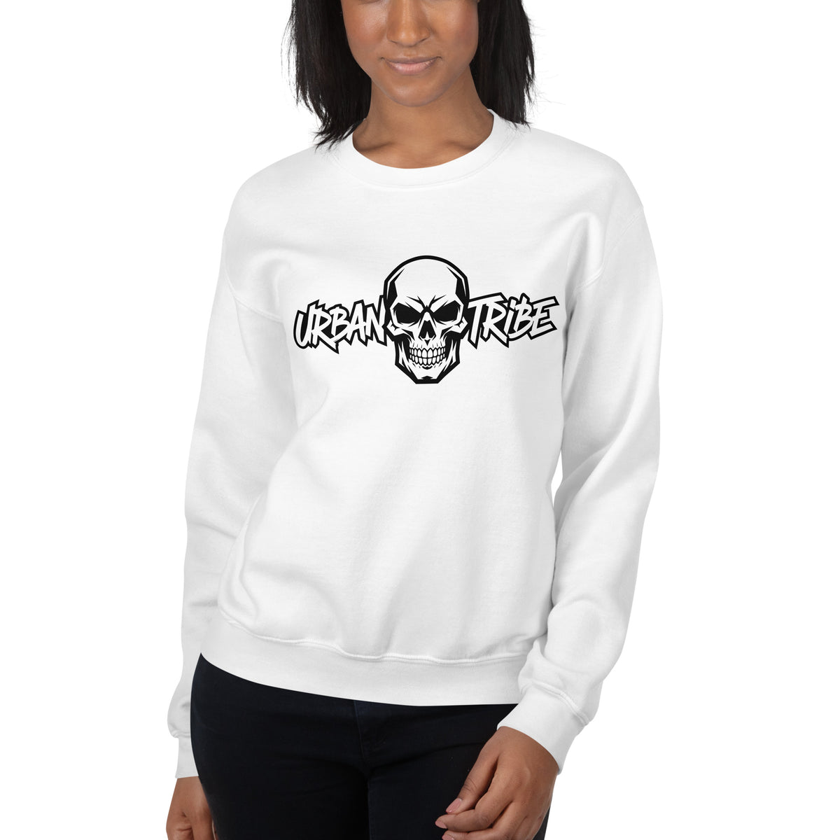 A woman wearing a white crewneck sweatshirt with a black graphic of a skull and the words 'URBAN TRIBE' across the chest, paired with black pants, against a plain white background.