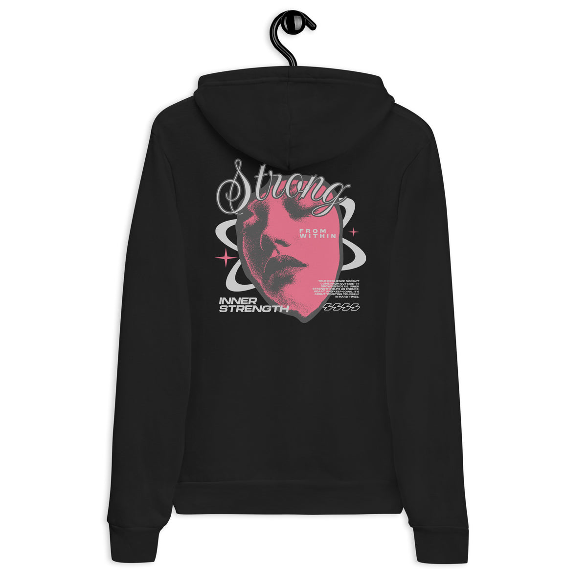 A black hoodie hanging on a black hanger against a plain white background, showing the back view with a large pink and white graphic print featuring a stylized face and the word 'Strong'.