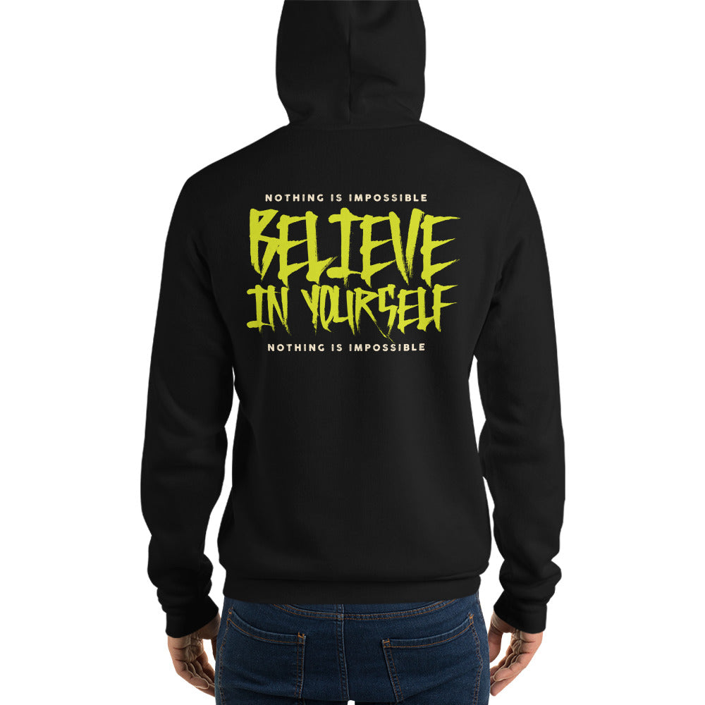A person shown from the back wearing a black hoodie with a large yellow and white graphic on the back reading 'BELIEVE IN YOURSELF' and smaller text 'NOTHING IS IMPOSSIBLE'. The person is also wearing blue jeans against a plain white studio background.