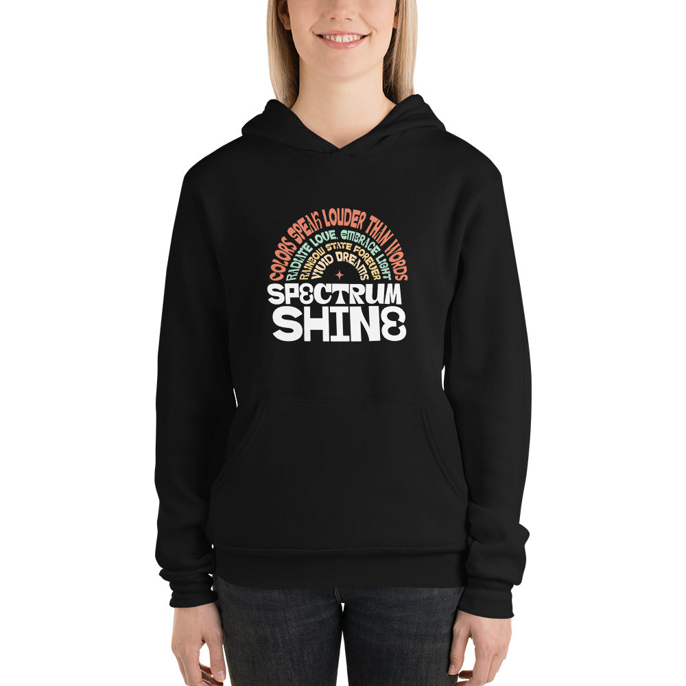 A woman wearing a black pullover hoodie with a colorful graphic on the chest that reads 'SPECTRUM SHINE' with smaller text arched above, shown against a plain white background.
