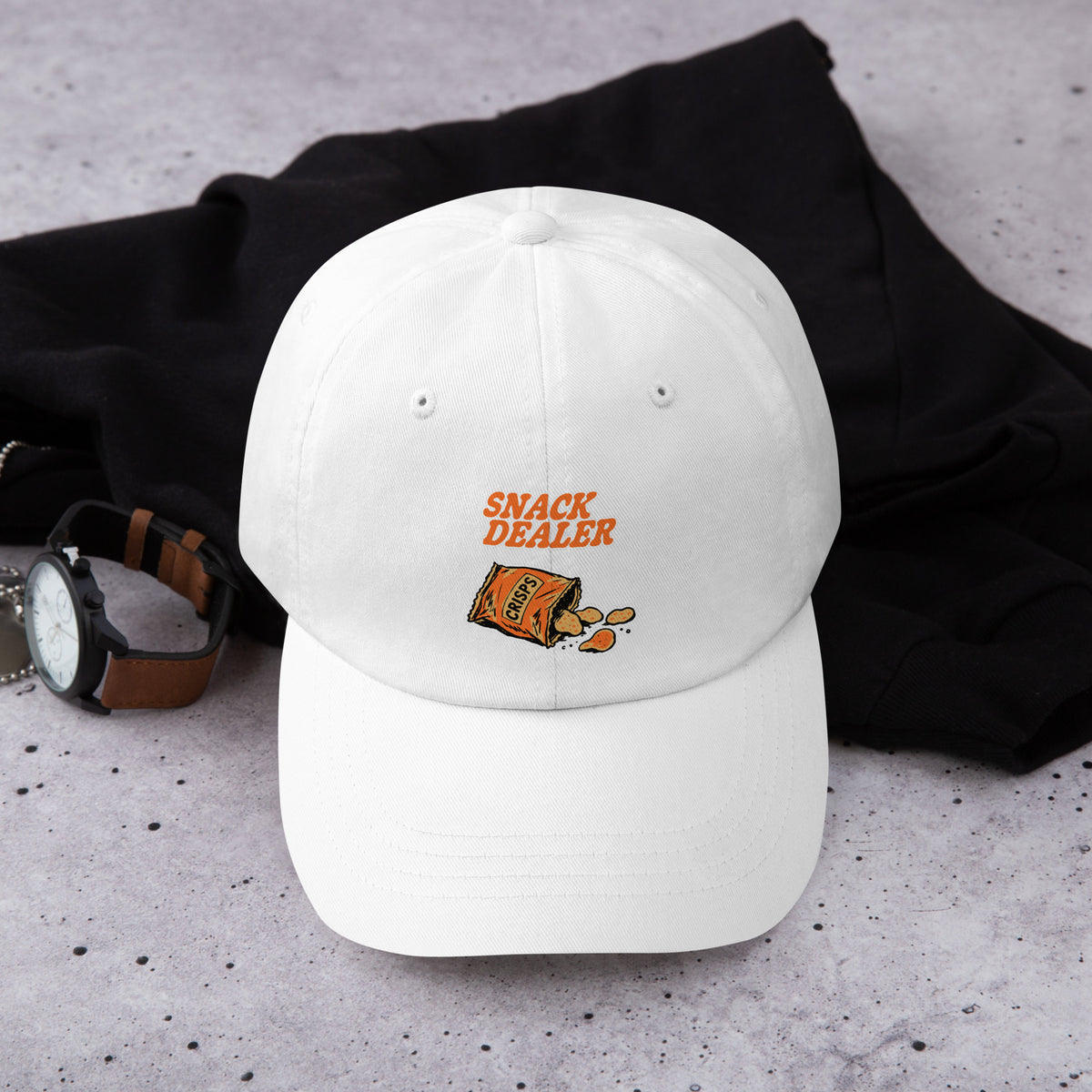 The Snack Dealer Dad Hat combines classic casual style with a fun twist. Made from durable cotton, it features an adjustable strap for a perfect fit. With its playful "Snack Dealer" embroidery, this hat is ideal for casual outings or relaxing at home. Pair it with your favorite tee for a laid-back look that showcases your personality while keeping you comfortable and stylish. Perfect for snack lovers everywhere!