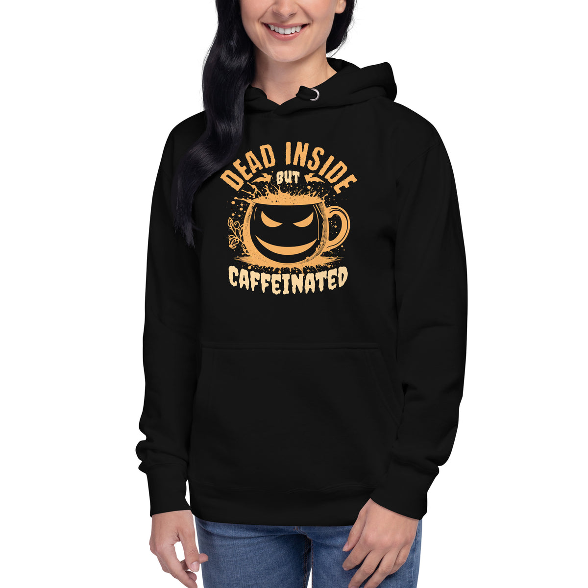 A woman wearing a black pullover hoodie with a distressed yellow graphic that reads 'DEAD INSIDE BUT CAFFEINATED' around a coffee cup illustration, shown against a plain white background.