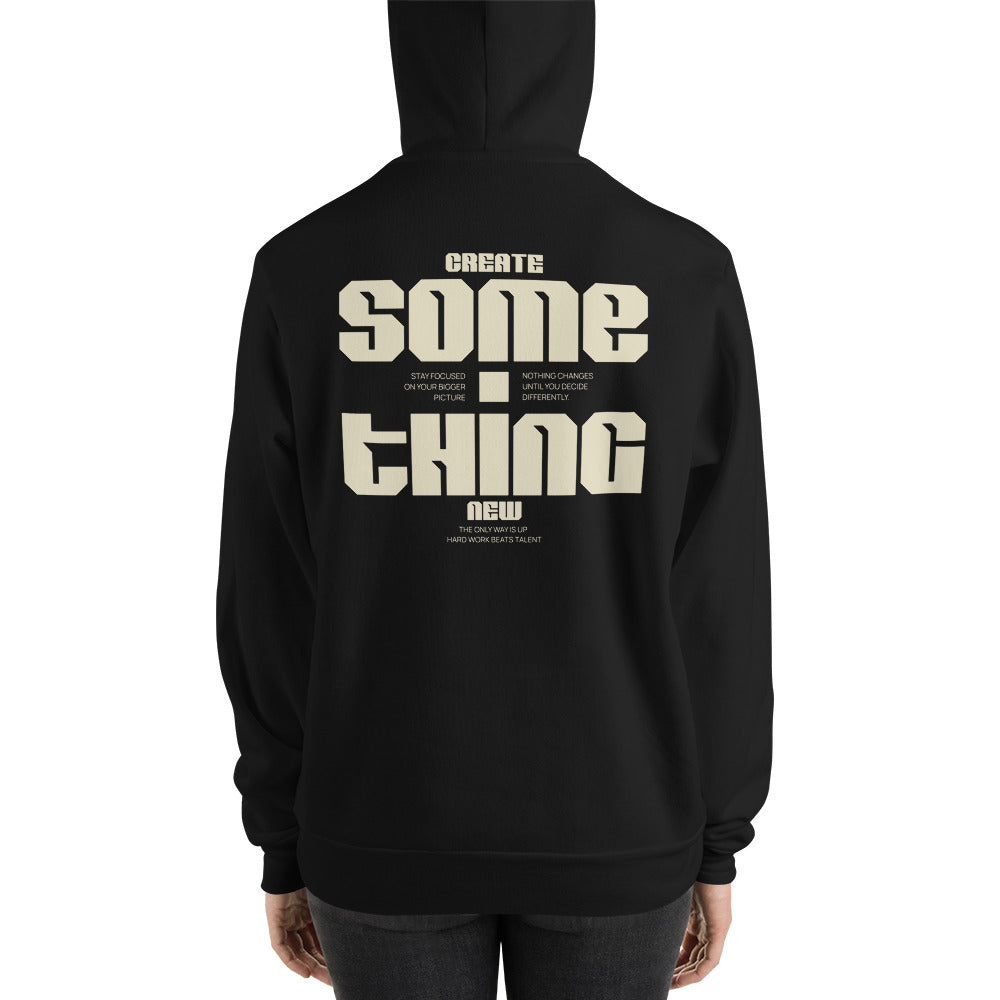 A person shown from the back wearing a black hoodie with a large cream-colored graphic text print on the back reading 'CREATE SOME THING NEW'.