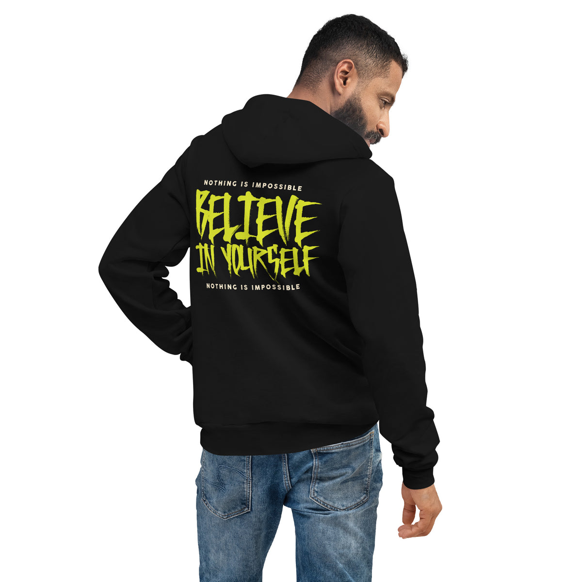A man wearing a black hoodie from the back, featuring a bright yellow graphic that reads 'BELIEVE IN YOURSELF' with 'NOTHING IS IMPOSSIBLE' above and below, paired with blue jeans against a plain white background.