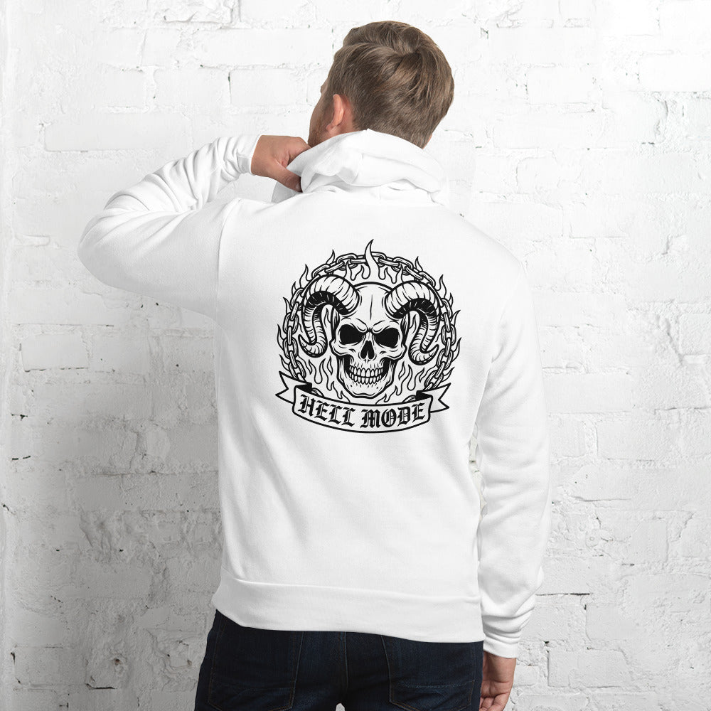 A man wearing a white hoodie with a large black graphic on the back, featuring a skull, horns, and the words 'HELL MODE', standing against a white brick wall.